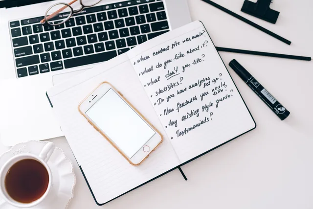 Top view of a workspace setup with a laptop, smartphone, notebook, and cup of coffee. Ideal for productivity. Defining a marketing automation target audience by workflow failure, not firm size
