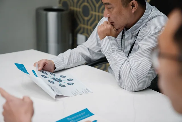 A businessman in a striped shirt thoughtfully reviews a printed document at his office desk. Choosing marketing automation tools with the operating problem defined before the demo
