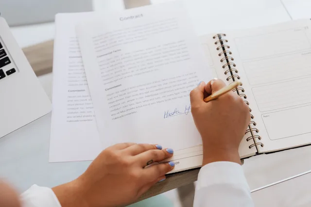Close-up of hands signing a contract on a desk with office supplies, symbolizing legal agreements. Marketing automation vendor due diligence, from corporate identity to exit evidence